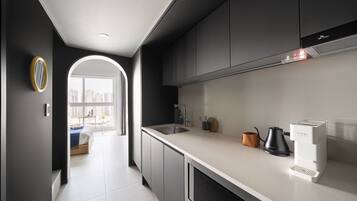 Una cocina moderna con horno integrado, cafetera y hervidor sobre la encimera.