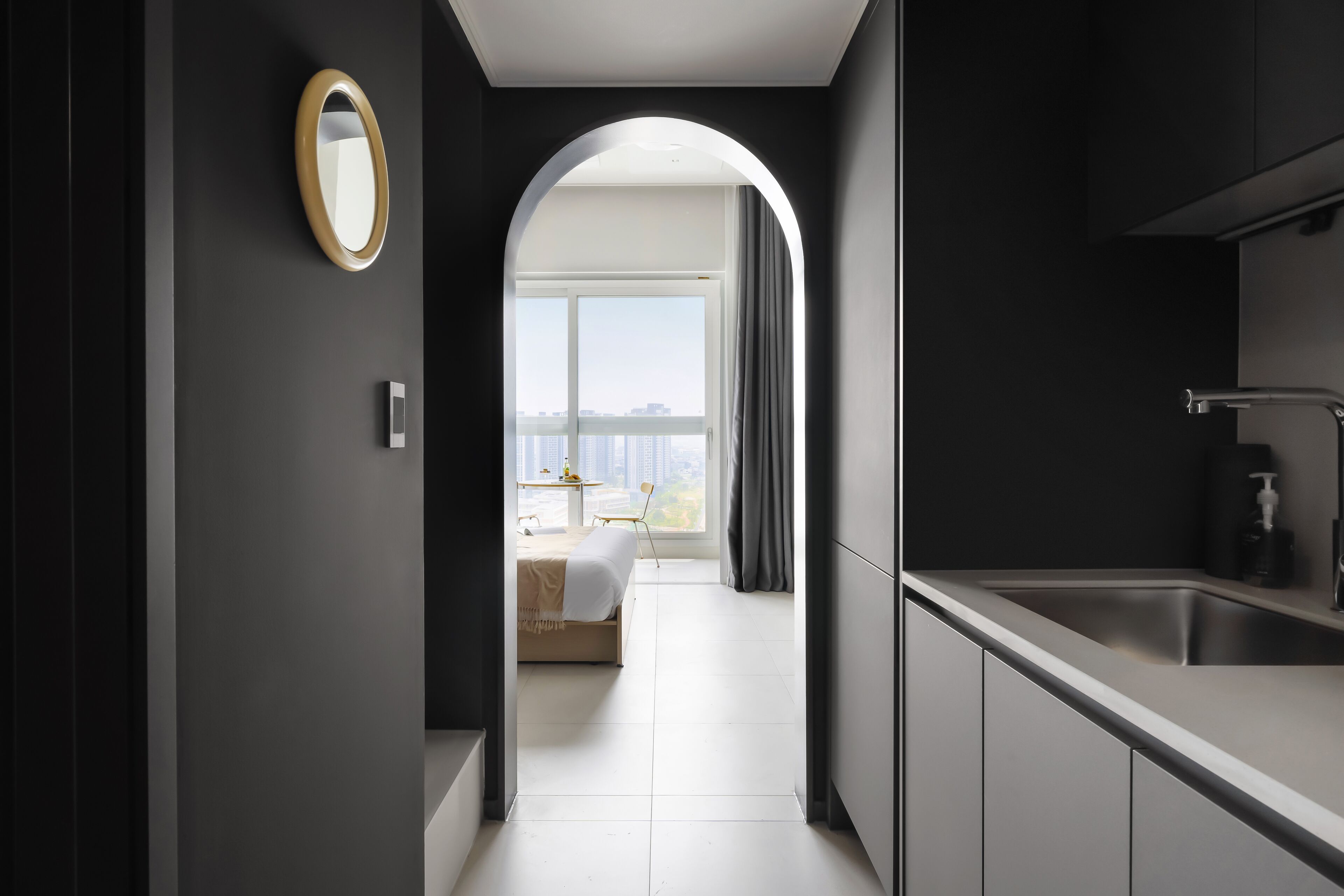 Une cuisine moderne dotée d’un évier encastré et donnant sur une chambre.