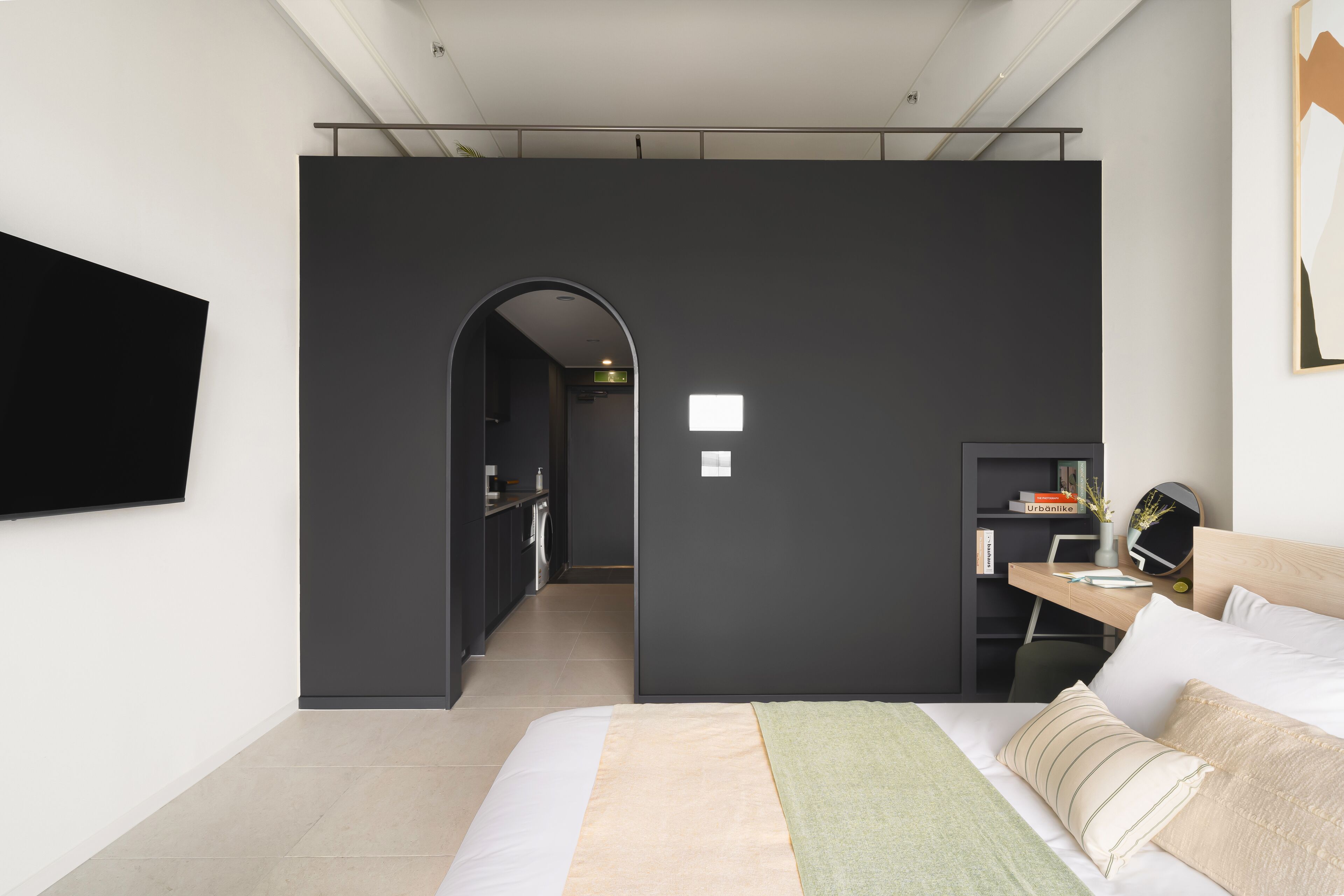 Ein modernes Hotelzimmer mit Bett, Schreibtisch und Fernseher.