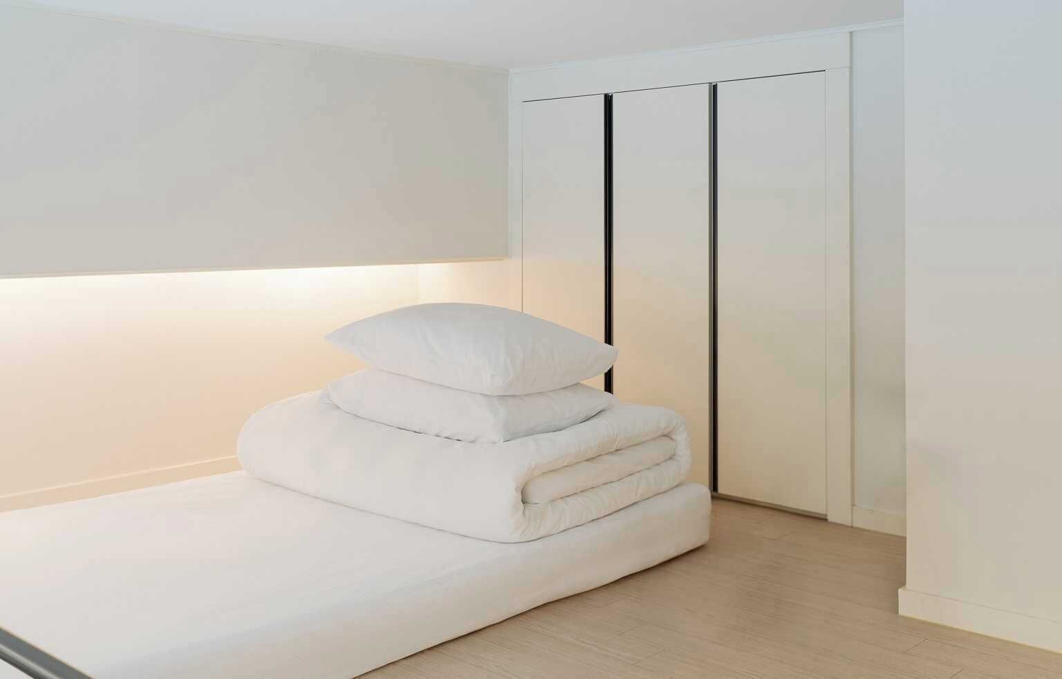 Una cama bien hecha con almohadas en una habitación minimalista con un armario corredero.
