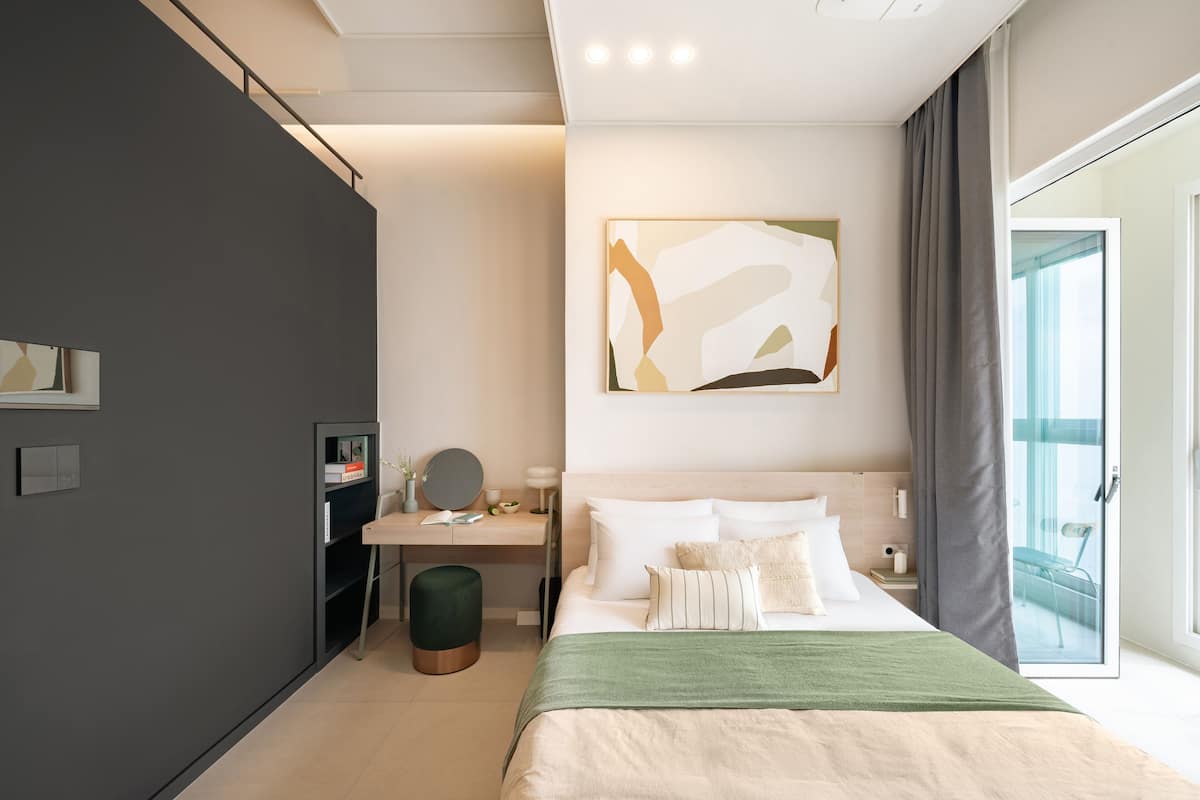 Habitació d'hotel moderna amb un llit gran, un escriptori, una cadira i vista a l'exterior.