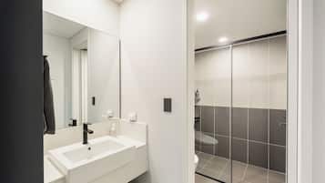 A modern bathroom with a white sink, mirror, and shower area.