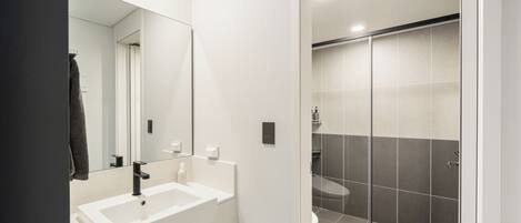 A modern bathroom with a white sink, mirror, and shower area.