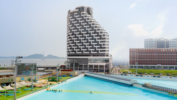 Un hôtel moderne à l’architecture originale, caractérisée par ses lignes courbes, doté d’un grand espace piscine et offrant une vue sur la mer.