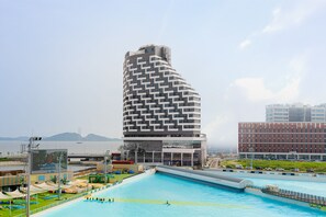 A modern hotel with a unique curved architecture, a large pool area, and a view of the sea. - Le collective Siheung Wavepark (Siheung)