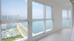 Un appartement situé dans un immeuble de grande hauteur, doté de grandes fenêtres offrant une vue sur le paysage urbain et un plan d’eau.