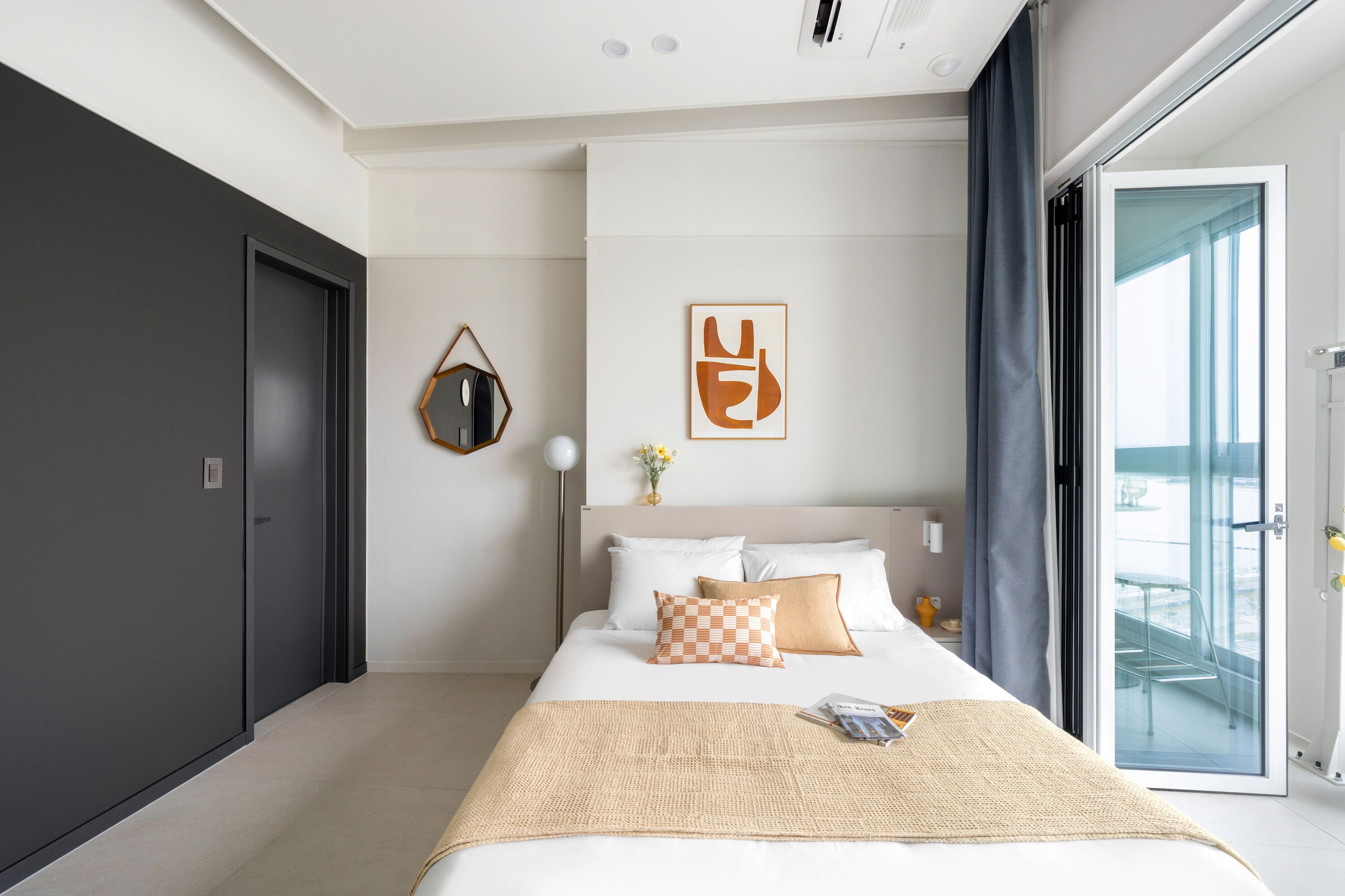 Ein modernes Hotelzimmer mit einem großen Bett, Blick durch eine Glastür und minimalistischer Einrichtung.