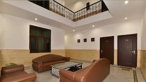A spacious lobby with leather sofas, a glass coffee table, and a staircase with decorative railings. - Hotel Divyansh By VRB Hotels (Dharamshala)