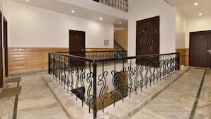 A multi-level interior with a marble staircase, metal railings, and wooden paneling. - Hotel Divyansh By VRB Hotels (Dharamshala)