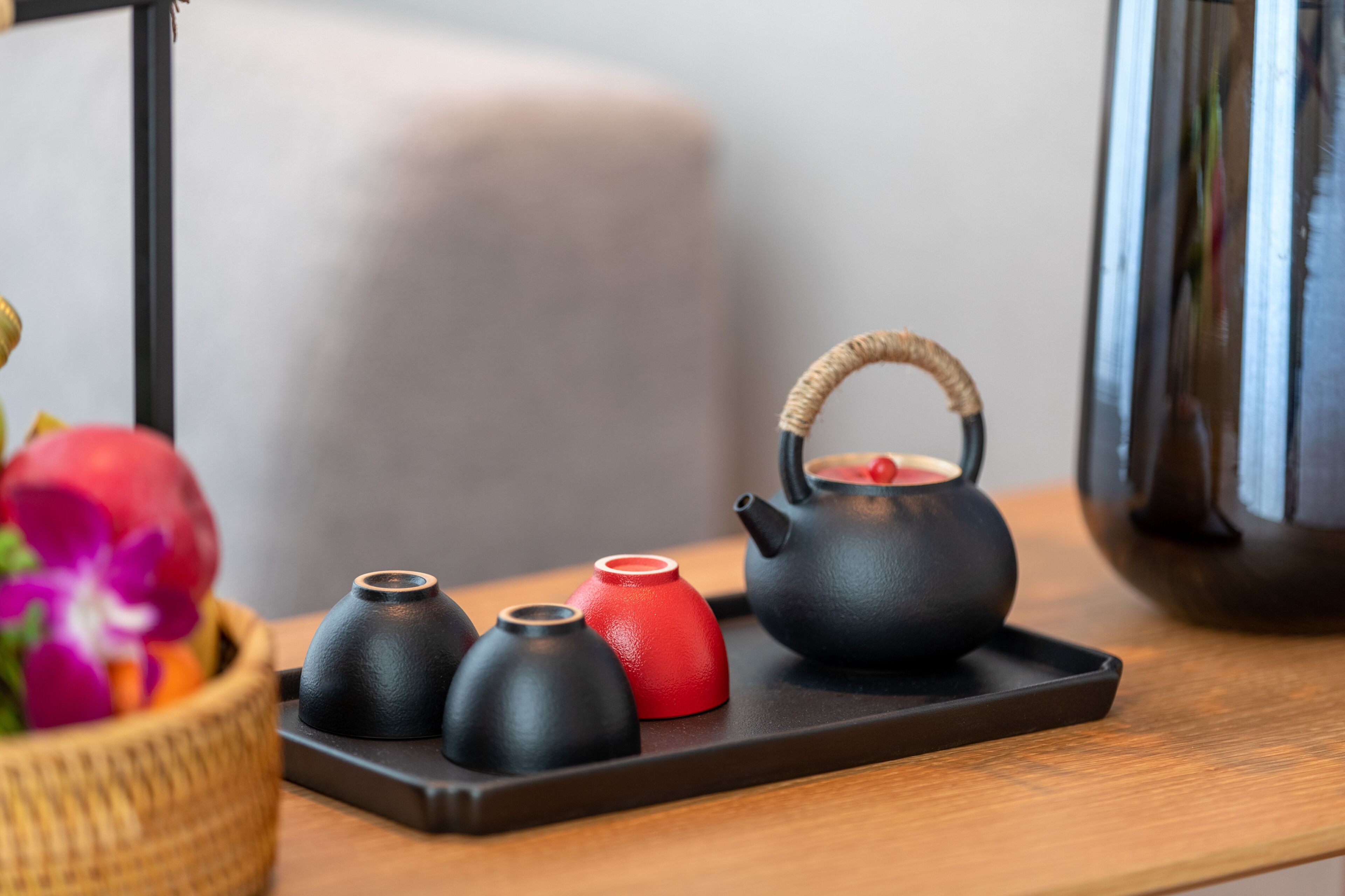 A tray with a black teapot and three small cups on a wooden table.