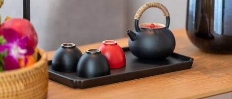A tray with a black teapot and three small cups on a wooden table.