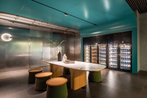 A modern interior with a central table, stools, and a beverage refrigerator.