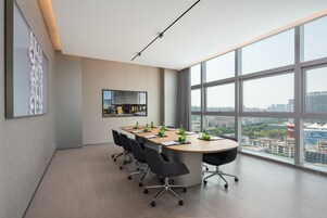 Una sala conferenze moderna con un grande tavolo, quattro sedie e vista sulla città attraverso ampie finestre.