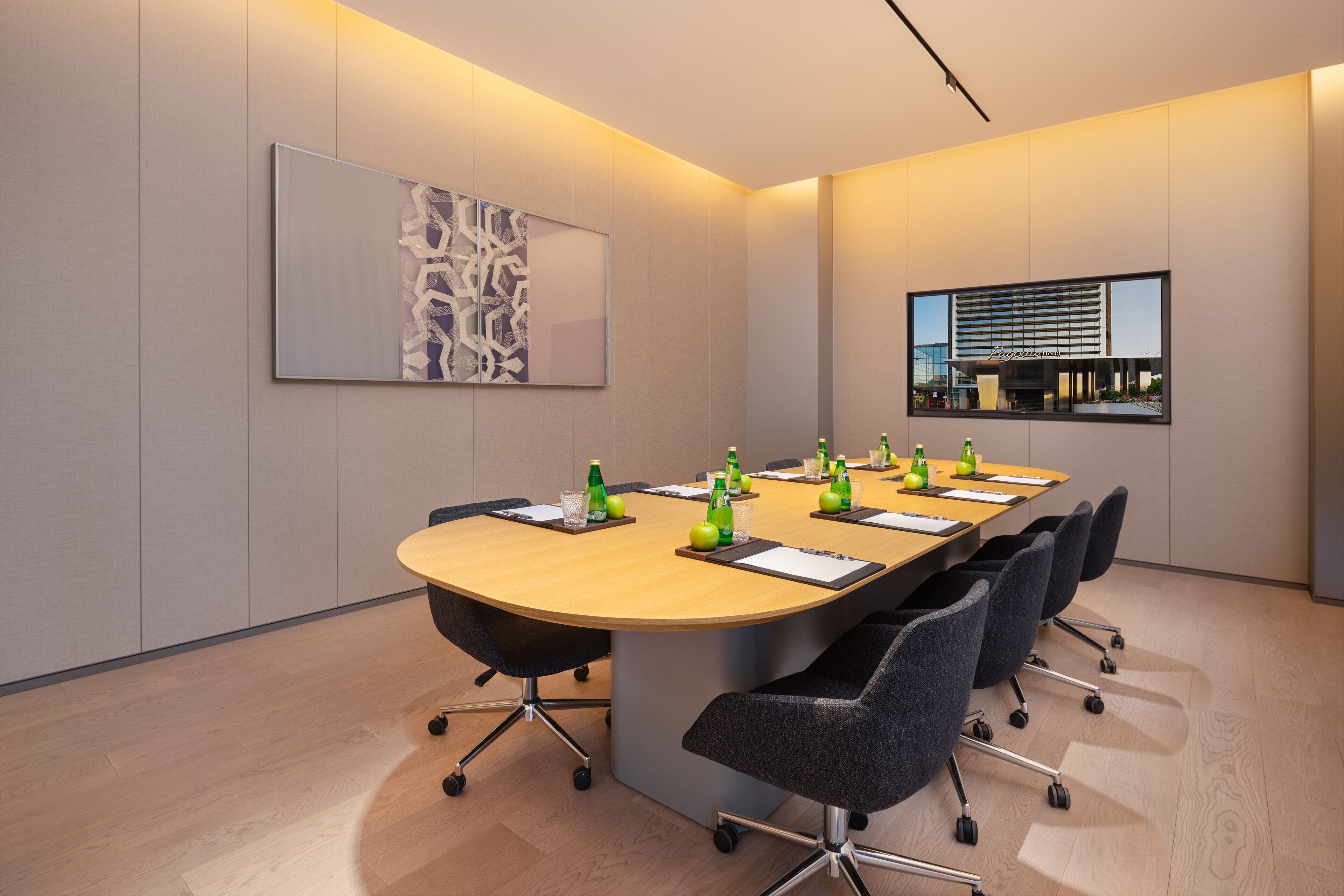 A conference room with a long table, chairs, and a large abstract painting on the wall.