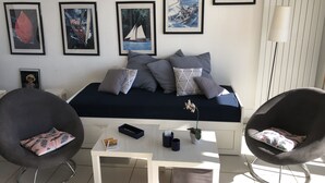 En moderne stue med sofa, to lænestole, sofabord og indrammede kunstværker på væggen.