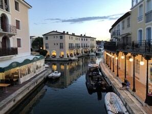 Un canal où sont amarrés des bateaux, des immeubles dotés de balcons et des espaces de restauration en plein air.