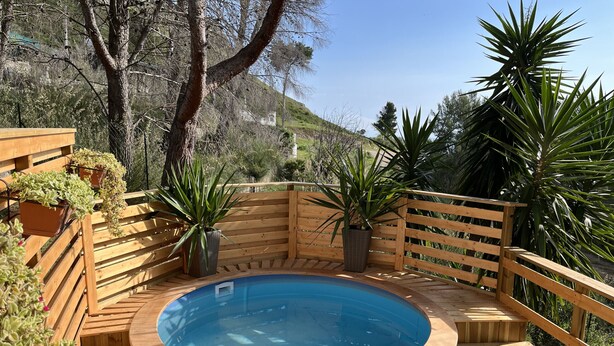 A wooden deck with a hot tub surrounded by potted plants and a wooden fence. - Wild Wild Nest Sperlongaresort (Sperlonga)