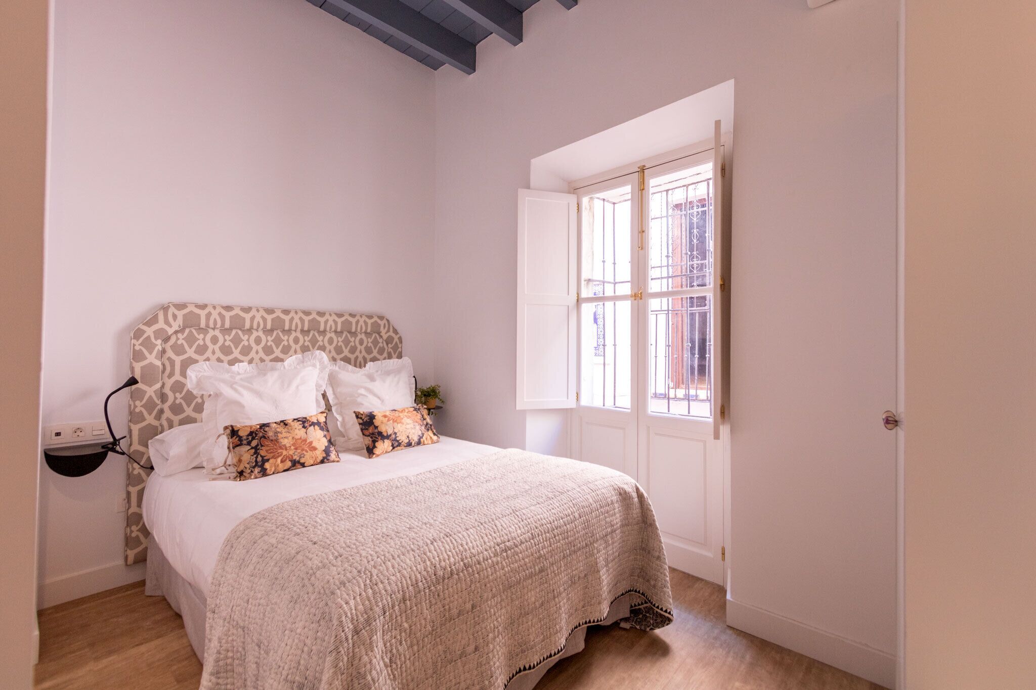 Un dormitorio con cama, mesita de noche, ventana con vistas y una puerta.