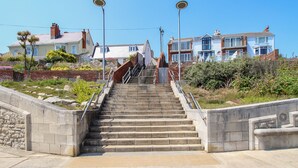 A set of concrete stairs leading up to a residential area with houses in the background. - Blanche Cottage (Weymouth)