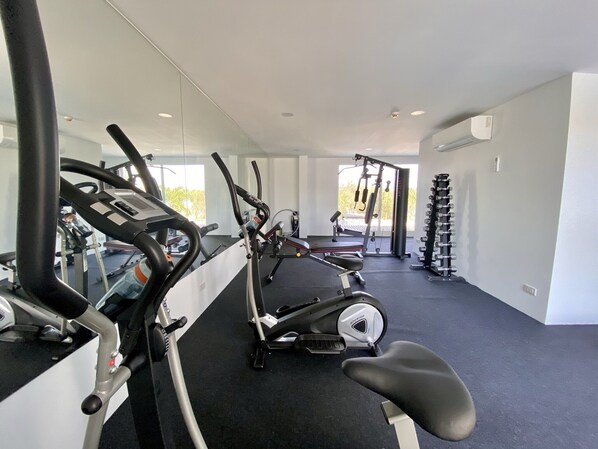 Une salle de sport équipée de machines de cardio, de matériel de musculation et d’un tapis de course.