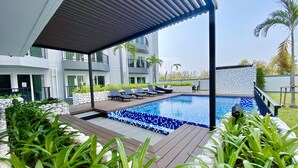 A modern pool area with a tiled pool, lounge chairs, and a covered seating area.