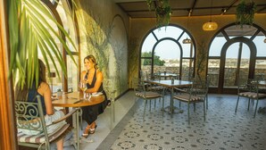 Un restaurante con terraza, paredes de piedra y plantas colgantes.