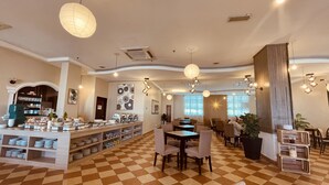 A hotel lobby with a checkered floor, a buffet area with various dishes, and several dining tables. - Putra Brasmana Hotel (Kuala Perlis)