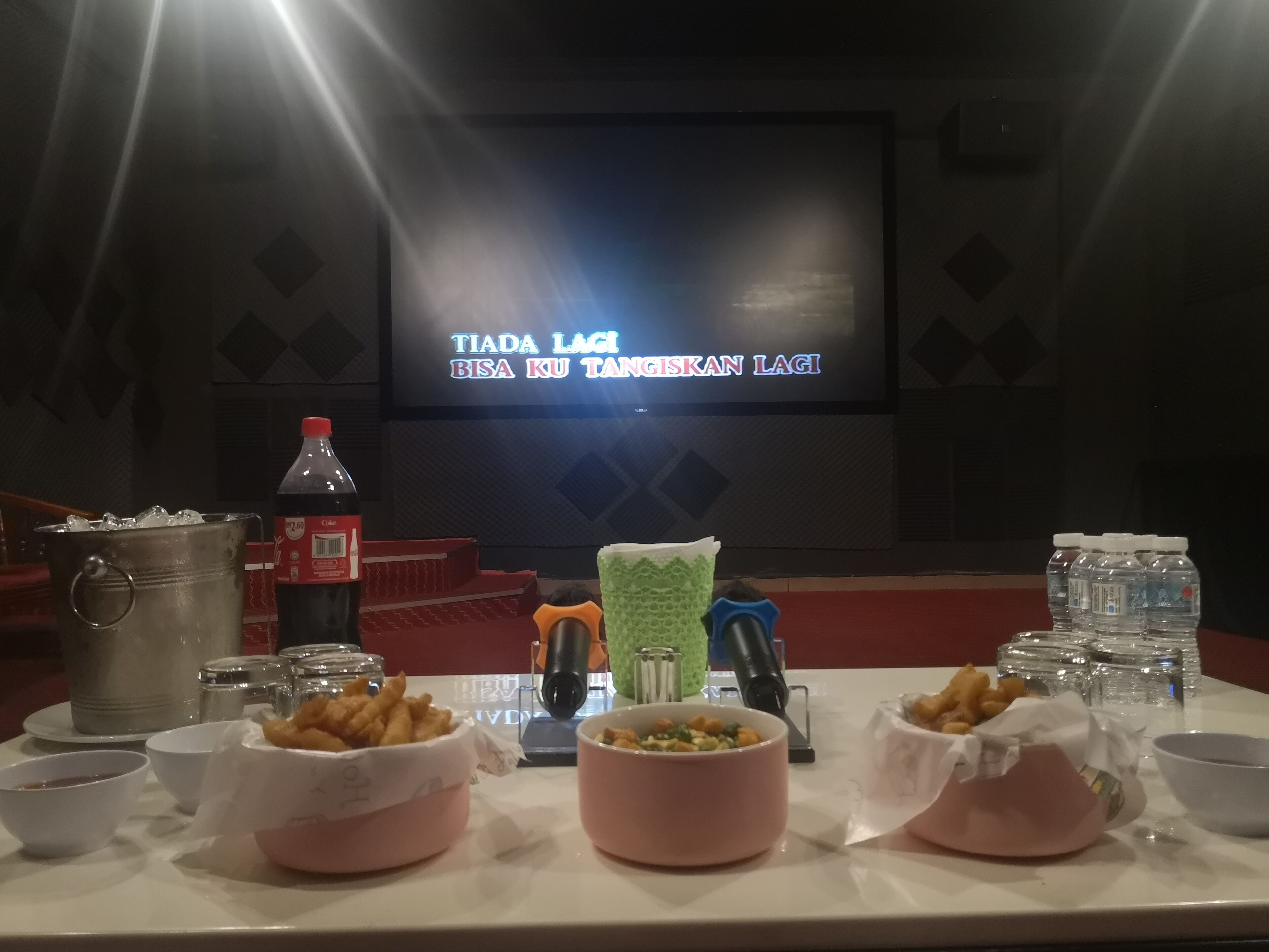 A dining table with food and drinks, a projector screen in the background, and a stage with a red carpet.