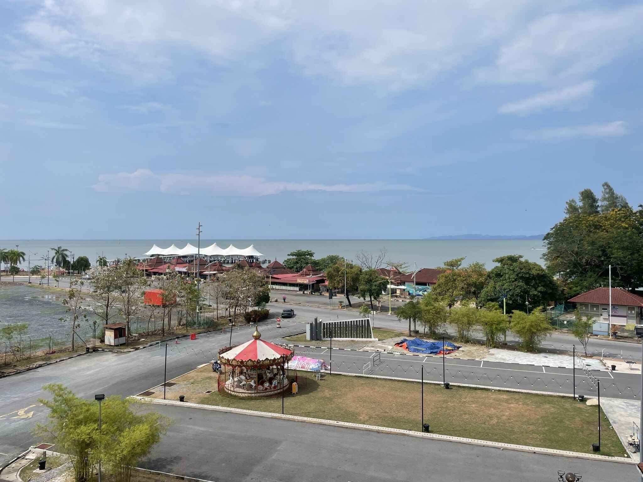 Eine Küstenlandschaft mit einer Drehscheibe, Restaurants im Freien und einer Straße, die zum Strand führt.