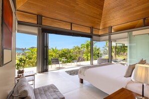 A modern bedroom with a large bed, a view of the ocean, and a balcony with outdoor seating. - Villa Benyasiri (Kamala)