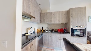 Een kleine keuken met houten kastjes, een roestvrijstalen spoelbak en een inbouwoven.