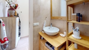 Een badkamer met een wit wastafelmeubel, houten planken en een douchehoek.