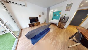 Ett kompakt bostadsutrymme med en soffa, en tv, ett litet skåp och en dörr.