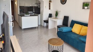A modern living space with a kitchen, a dining area, and a sofa with cushions. - Bel Appartement Avec Piscine , le 600 (ROSES)
