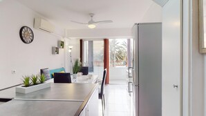 A modern kitchen with a dining area, a ceiling fan, and a view to the outside. - Bel Appartement Avec Piscine , le 600 (ROSES)