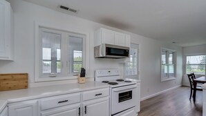 Una cocina moderna con armarios blancos, un microondas de acero inoxidable y un horno empotrado.