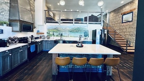 Una cucina moderna con isola centrale, sgabelli da bar e vista su un paesaggio montuoso attraverso un'ampia finestra.