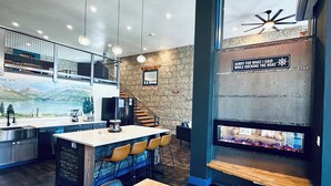 Una cucina moderna con un'isola grande, sedie in legno e un tavolo da pranzo. Si vede una scala con un muro rustico e un affresco che raffigura un lago.