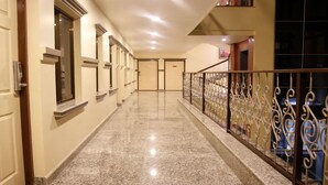 A hotel corridor with a polished granite floor, white doors, and a decorative wrought iron railing. - MeroStay 159 Hotel AP (Kathmandu)