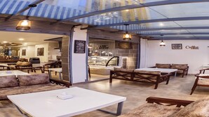 A modern café with a glass ceiling, wooden furniture, and a visible coffee bar. - MeroStay 159 Hotel AP (Kathmandu)