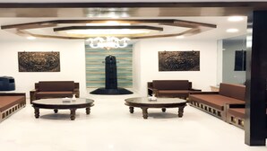 A modern lobby with two sofas facing a central pillar, a chandelier, and artwork on the walls. - MeroStay 159 Hotel AP (Kathmandu)