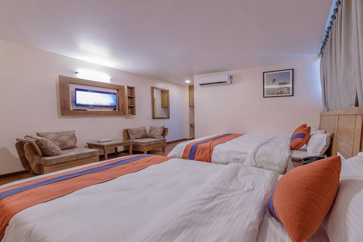 Une chambre d’hôtel avec deux lits, une télévision, un bureau et une chaise.
