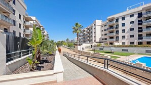A modern residential building with balconies, a swimming pool, and a landscaped garden area. - Global Vacacional: Apartment with large terrace in Canet (Canet d´en berenguer)