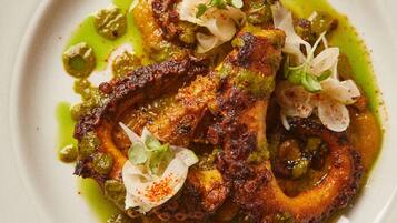Plat de menjar amb salsa verda, decorat amb elements blancs i verdosos.