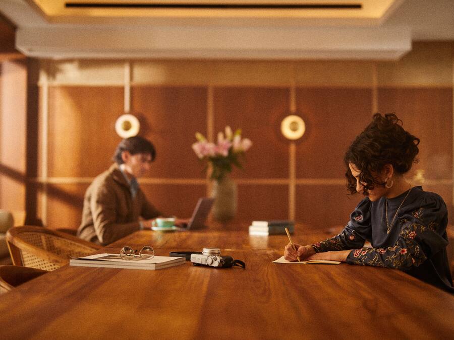A wooden conference table with a laptop, a camera, and a notebook.