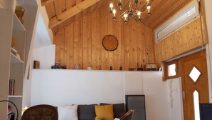 A cozy living room with a wooden ceiling, a sofa with cushions, a television, and a dining area with a table and chairs. - 1 Bedroom Private vacation home in Vaskeresztes (Vaskeresztes)