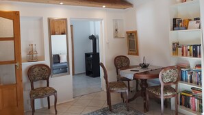 A cozy dining area with a wooden table, four chairs, a bookshelf, and a fireplace. - 1 Bedroom Private vacation home in Vaskeresztes (Vaskeresztes)