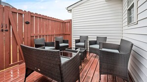 Un patio al aire libre con muebles de mimbre y una terraza de madera.