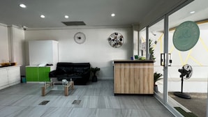 A modern office space with a black leather sofa, a wooden reception desk, and a green cabinet. - Royal Vista (Patong)
