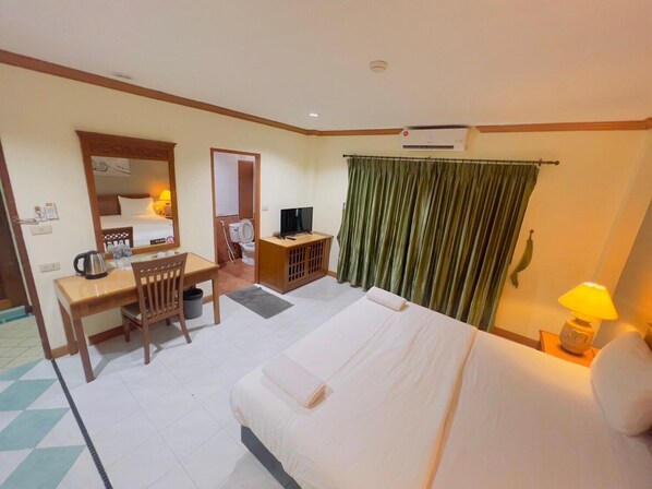 Une chambre d’hôtel comprenant un lit, un bureau avec une chaise, une télévision, une salle de bain et un rideau.